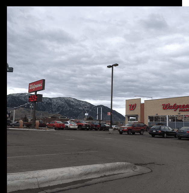 Walgreens store with mountain backdrop and cars.