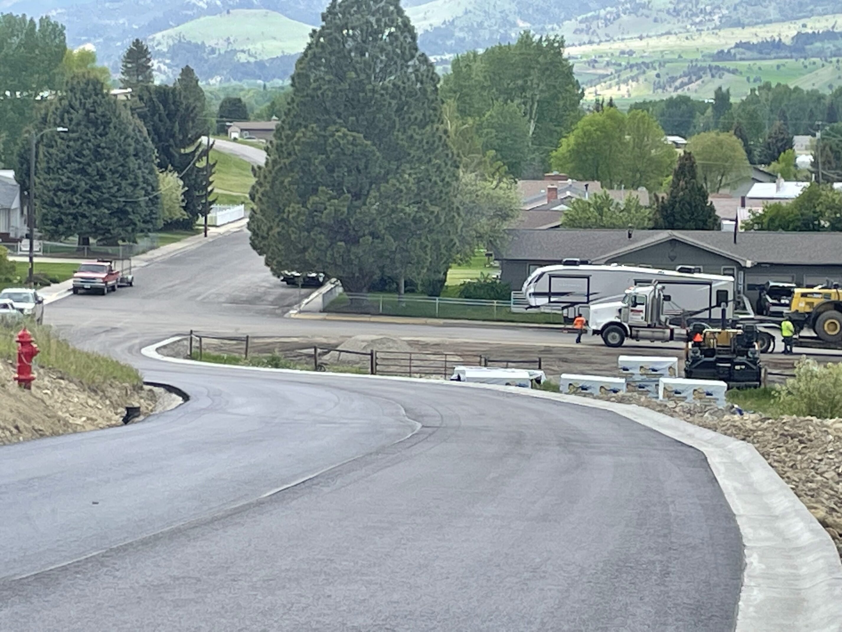 Road construction in residential neighborhood with trees.